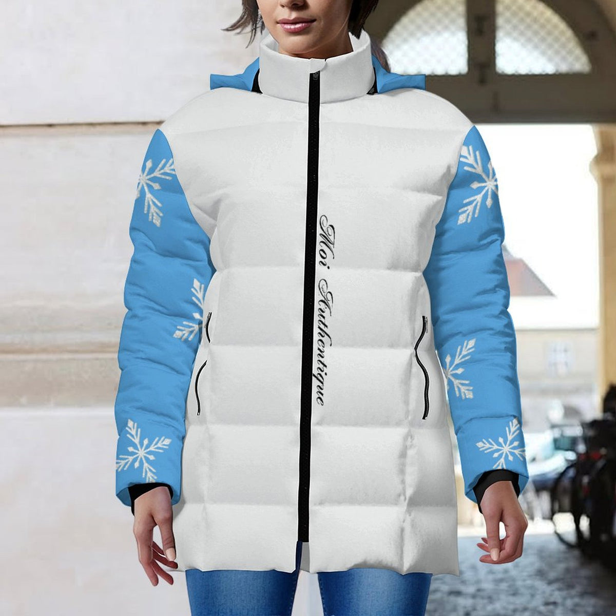 White puffer jacket with blue sleeves and snowflake patterns worn by a person.