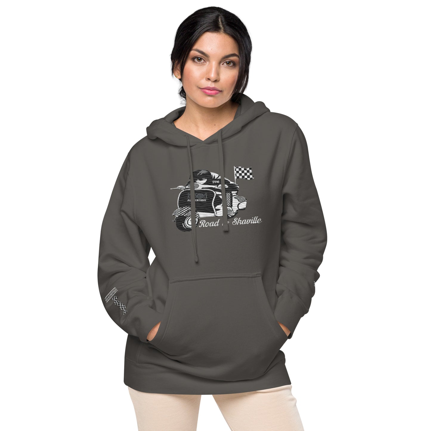 A woman wearing a black pigment-dyed hoodie with front and sleeve embroidery featuring a vintage moped design and the text 'Road to Skaville'.