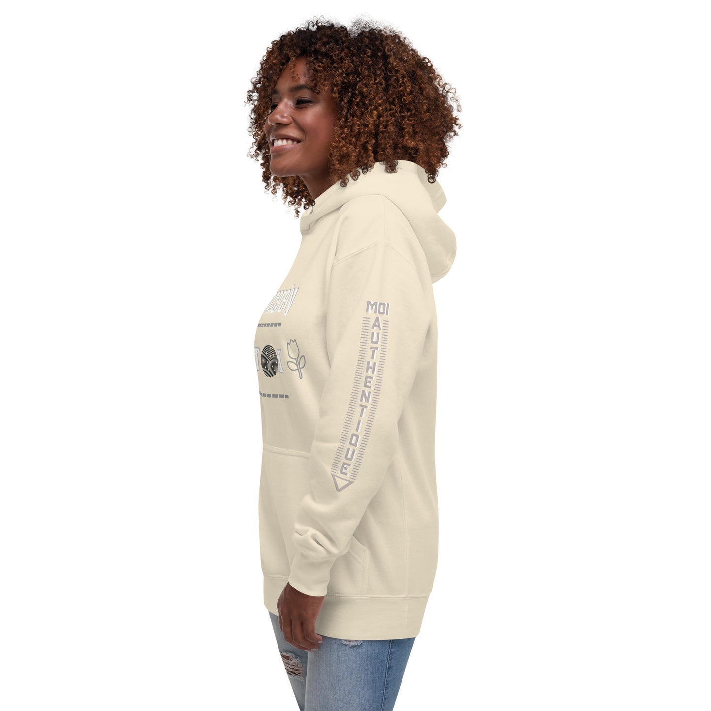 Side view of a woman wearing a beige unisex hoodie with a front pouch pocket, standing against a white background.