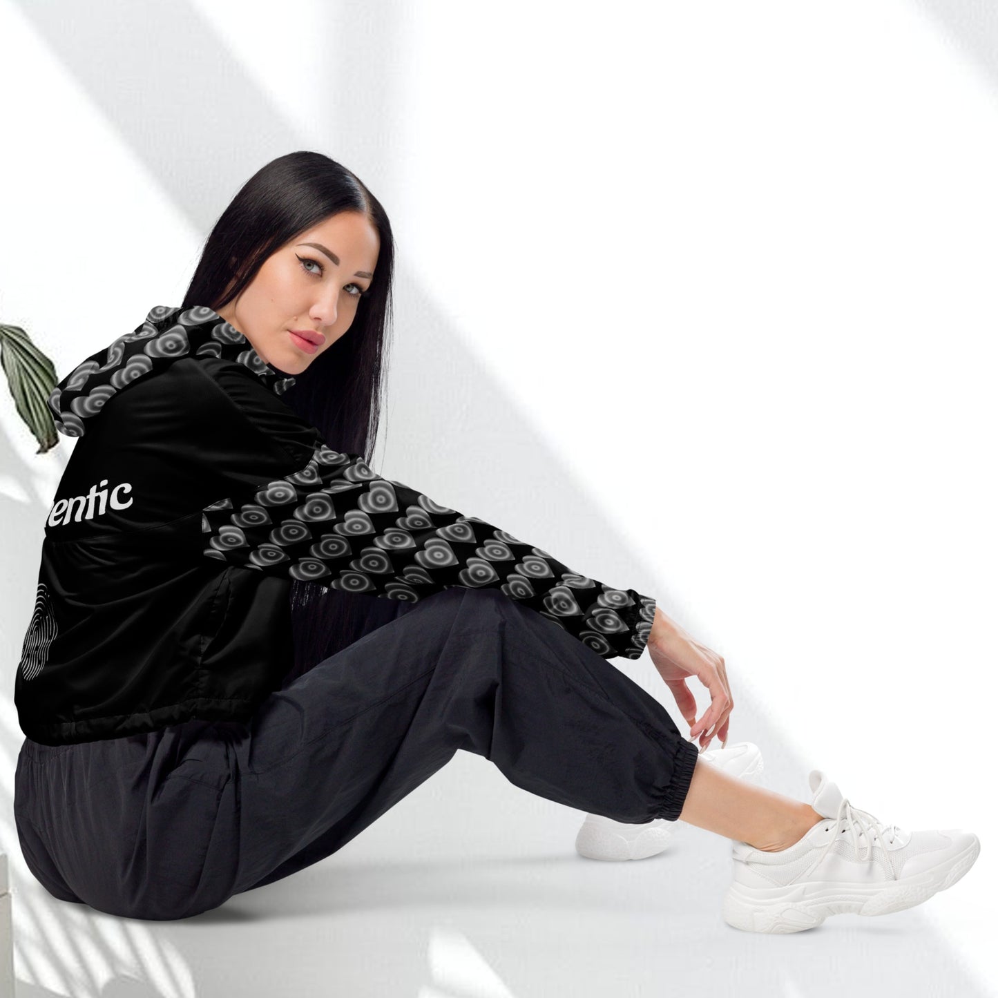View of a woman wearing a black cropped windbreaker with a hood, featuring side-slit pockets and a breathable mesh lining.