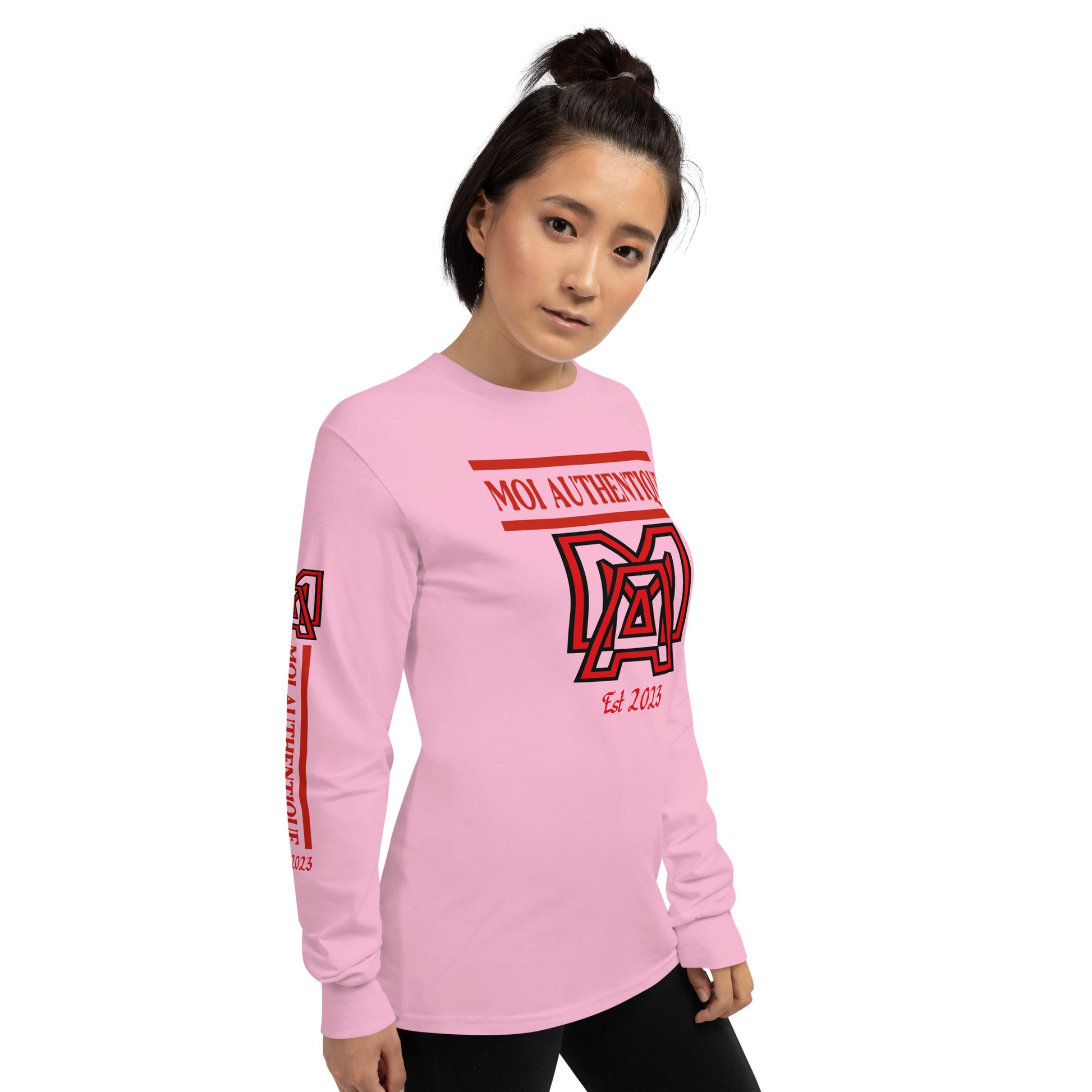 A Side-on view of a woman wearing a long-sleeved pink shirt with red text and graphics, including the brand name 'Moi Authentique' across the chest