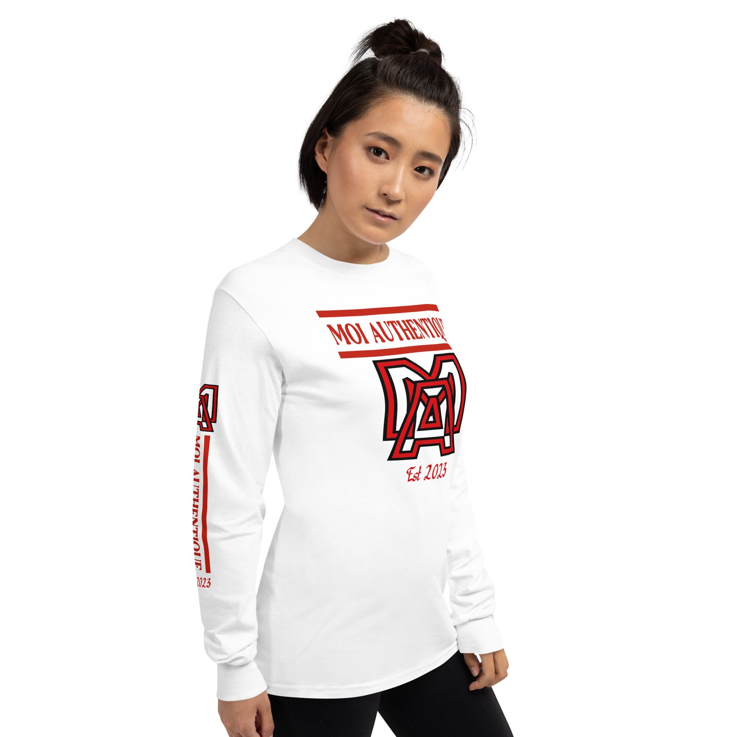 Side-on view ofa woman wearing a long-sleeved white shirt with text and logos on it, standing against a plain background.