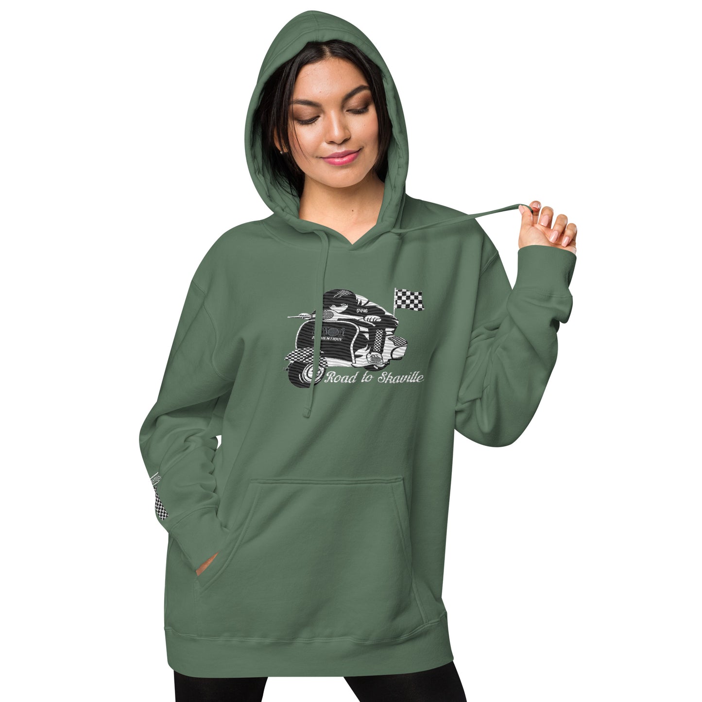 A person wearing a green pigment-dyed hoodie with front and sleeve embroidery featuring a vintage moped design and the text 'Road to Skaville'.