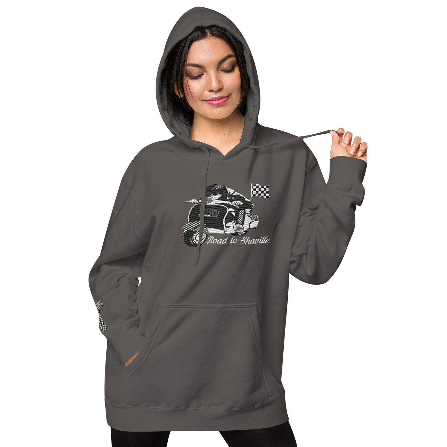A woman wearing a black pigment-dyed hoodie with front and sleeve embroidery featuring a vintage moped design and the text 'Road to Skaville'.