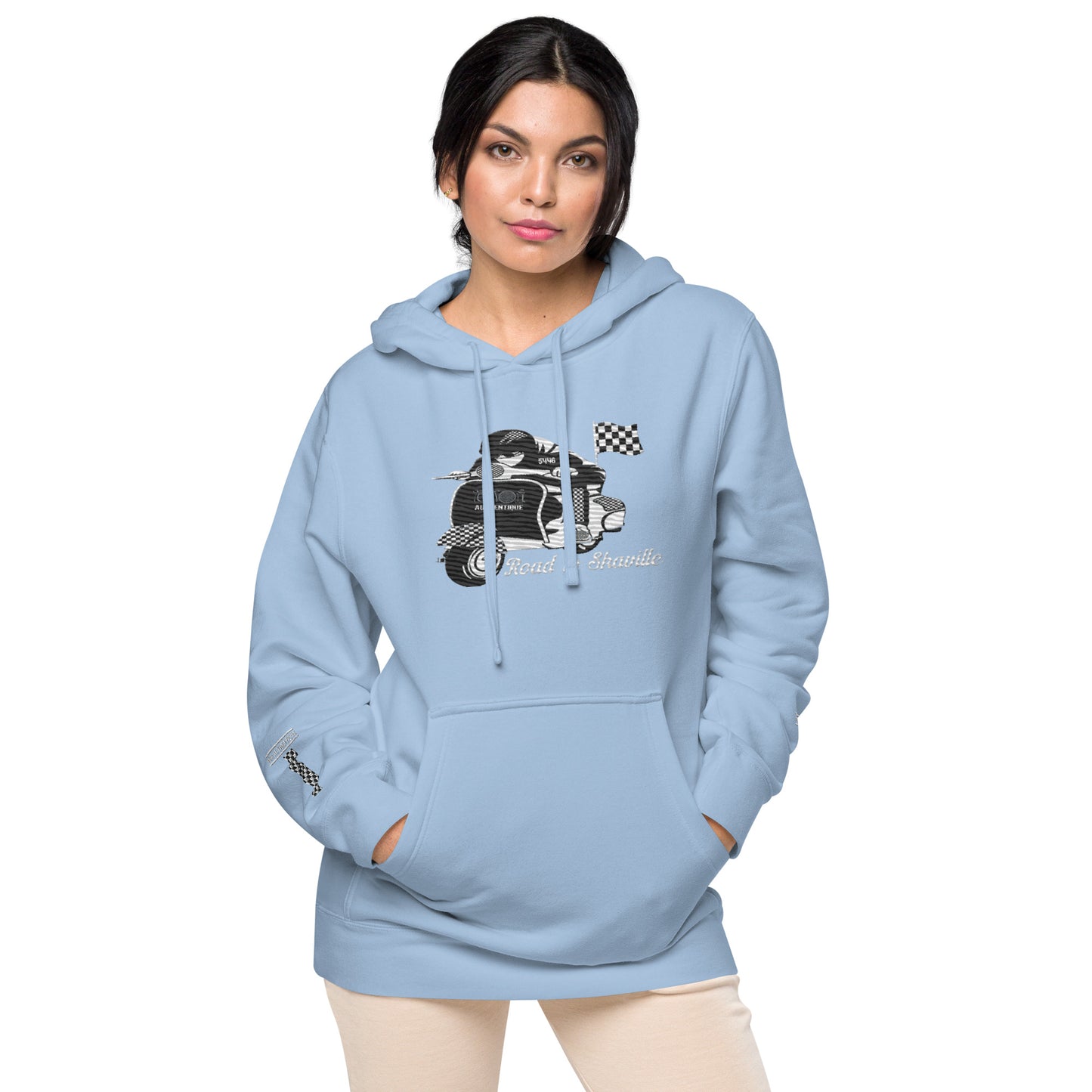 A woman wearing a light blue pigment-dyed hoodie with front and sleeve embroidery featuring a vintage moped design and the text 'Road to Skaville'.