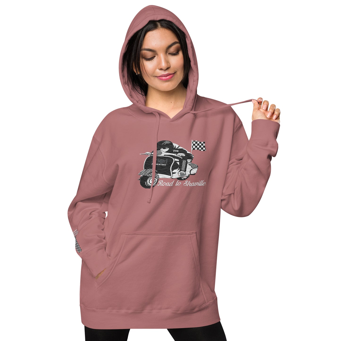 A woman wearing a maroon pigment-dyed hoodie with front and sleeve embroidery featuring a vintage moped design and the text 'Road to Skaville'.