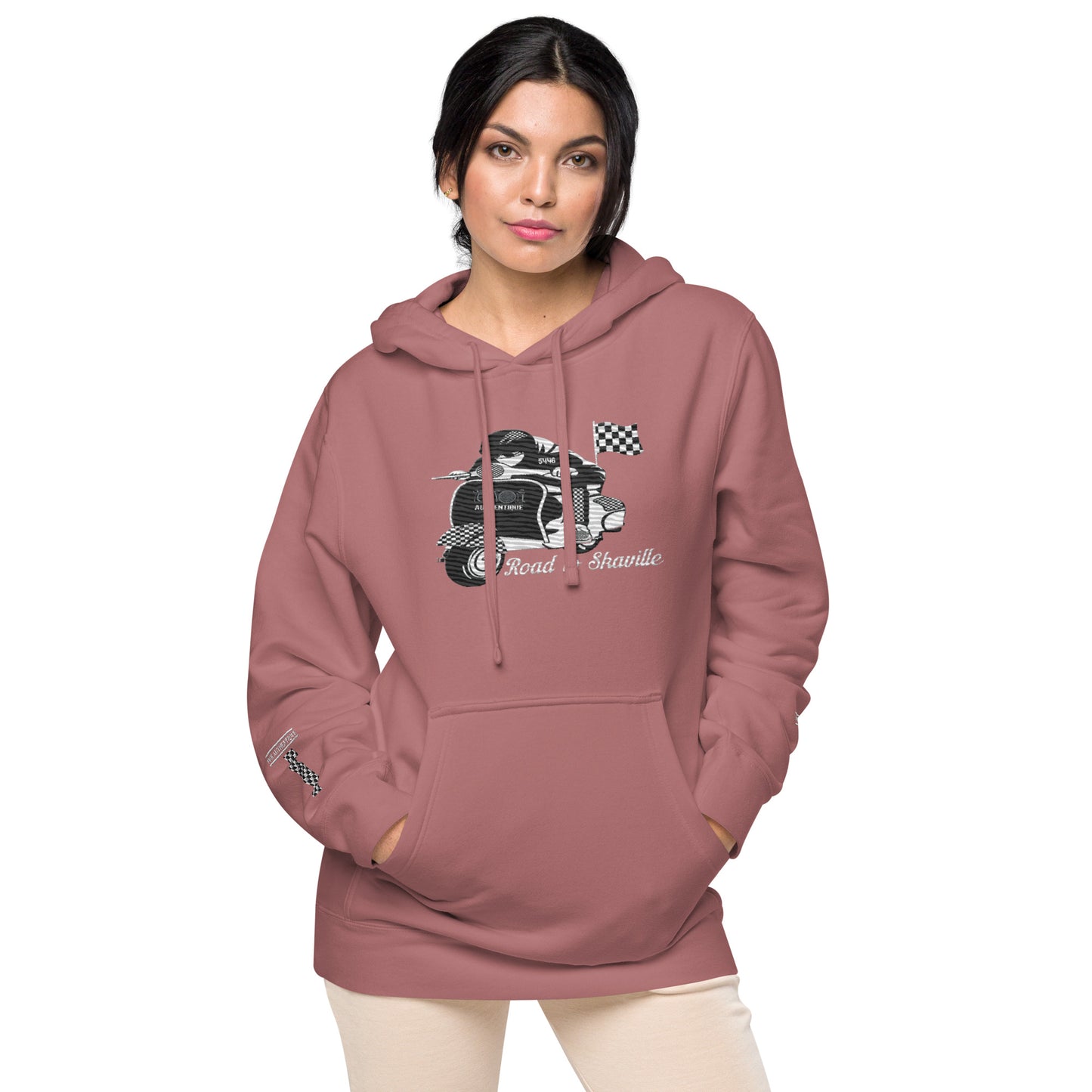 A woman wearing a maroon pigment-dyed hoodie with front and sleeve embroidery featuring a vintage moped design and the text 'Road to Skaville'.