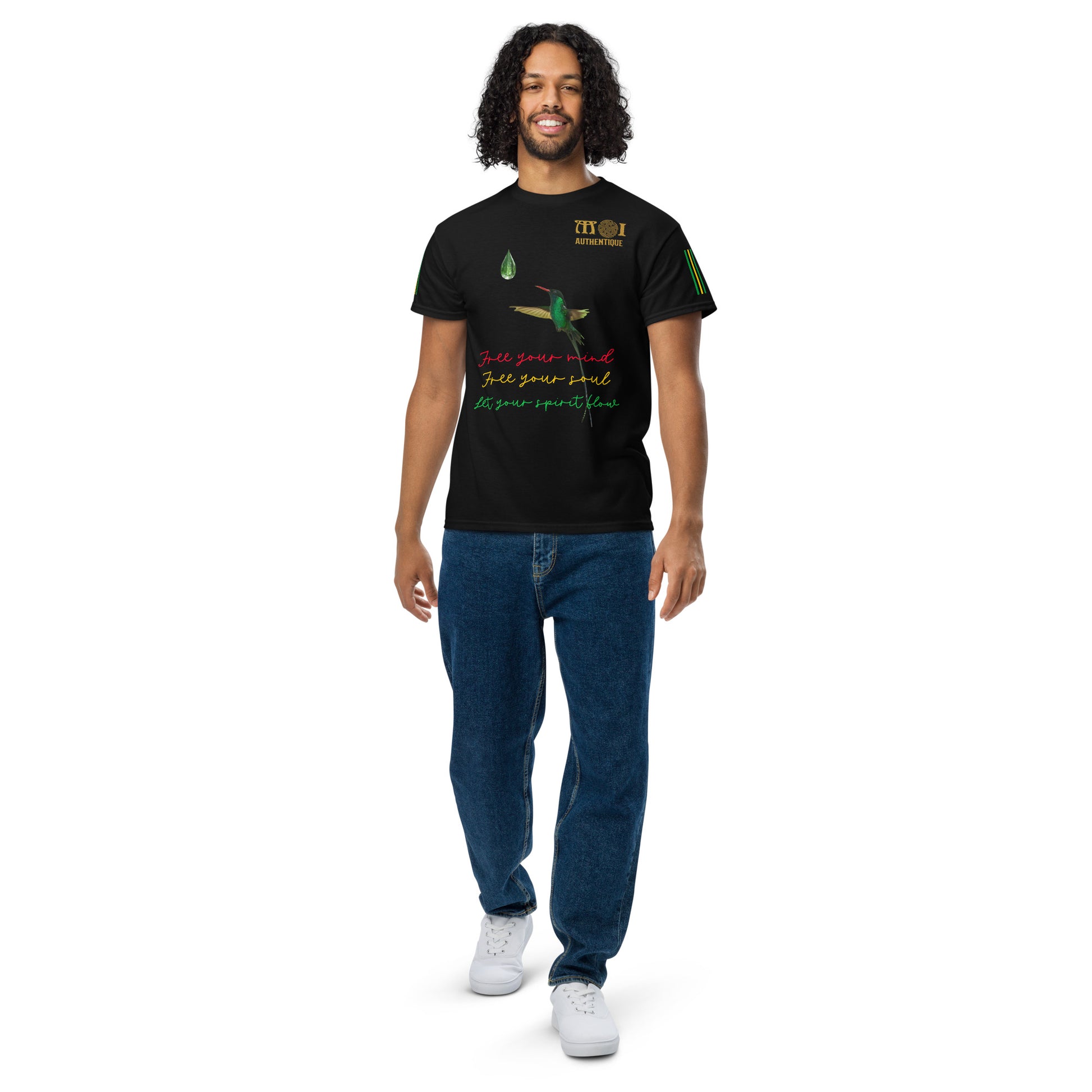 A smiling person with short hair wearing a black Unisex DryBlend T-Shirt with colourful text and graphics on it, and also wearing blue jeans